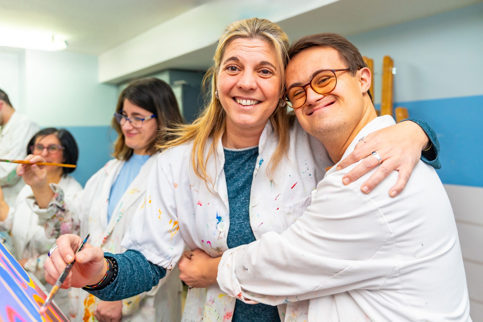 Man with down syndrome embracing his painting teacher